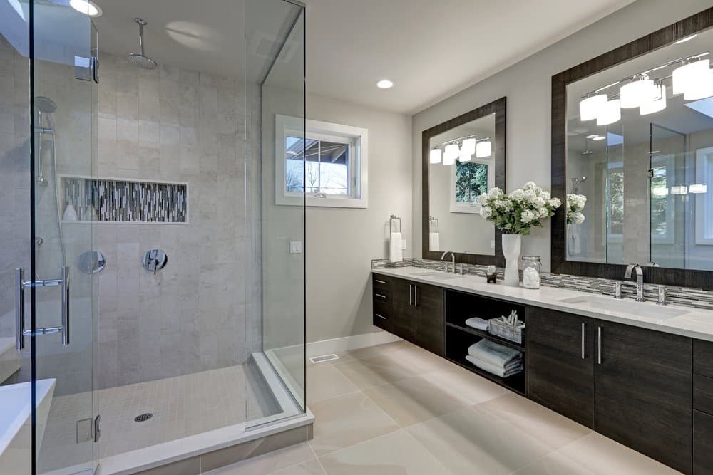 Spacious bathroom in gray tones with heated floors, walk-in shower, double sink vanity and skylights.