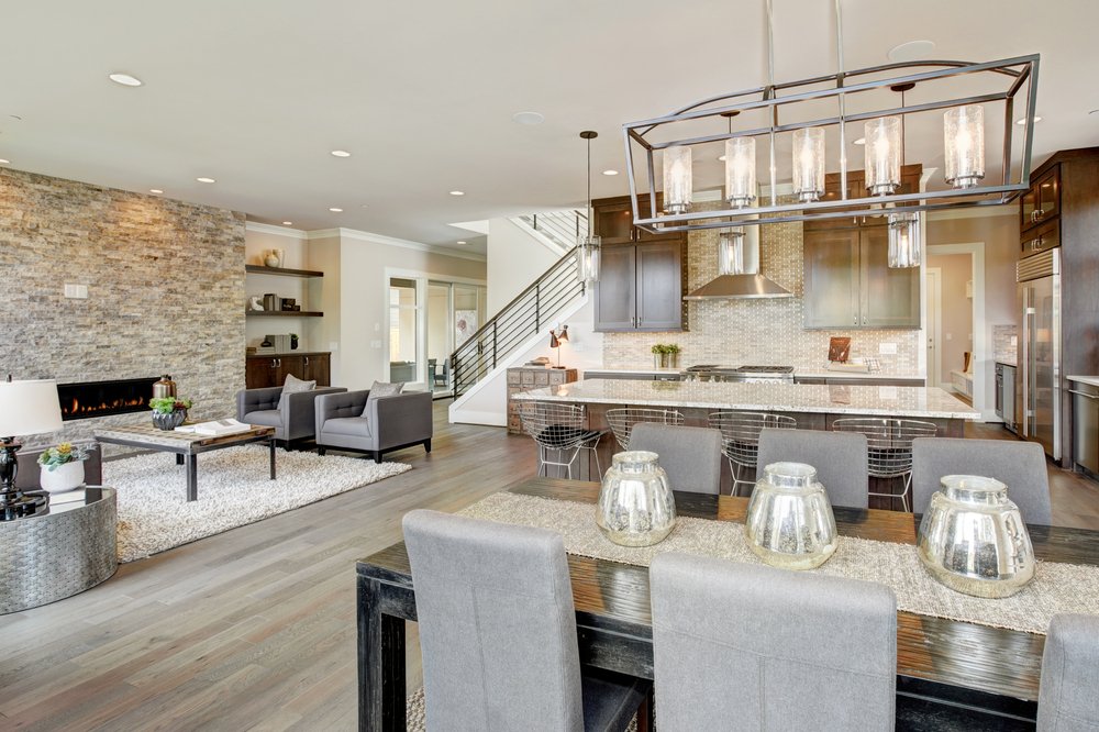 Open plan kitchen equipped with high-end appliances opens to the dining room and the great room with a floor to ceiling stone fireplace