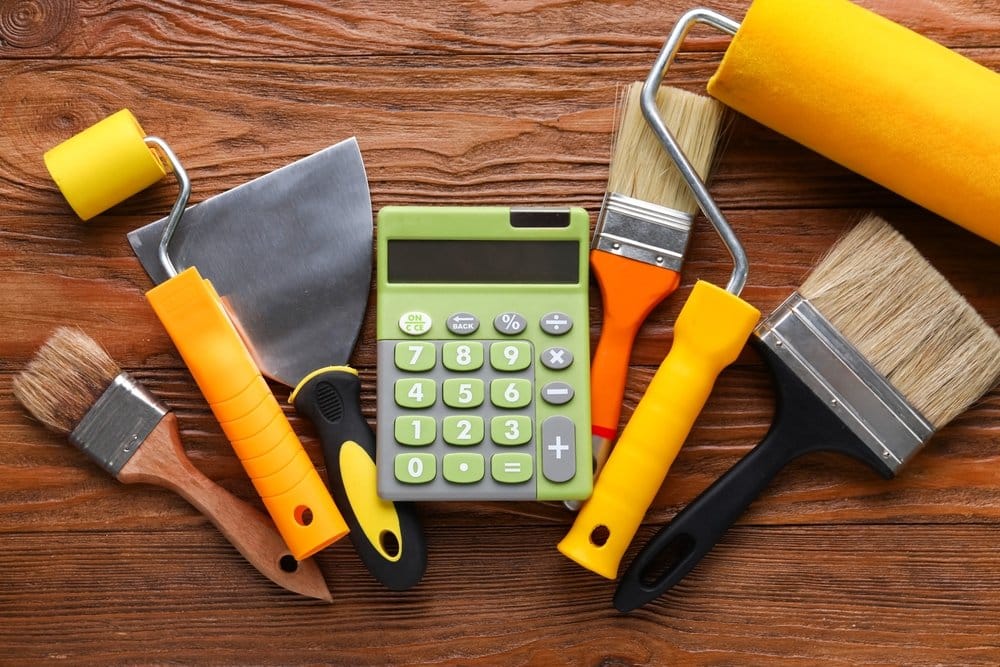 Calculator and painting tools on wooden background. home renovations concept